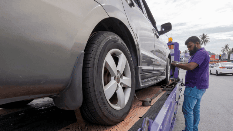 A tow truck operator securing a vehicle during a repossession process.