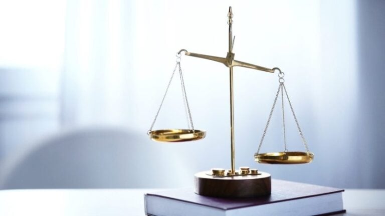 Golden balance scale of justice placed on top of a book