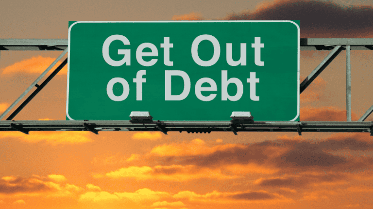 A highway sign with the message "Get Out of Debt" against a sunset background.