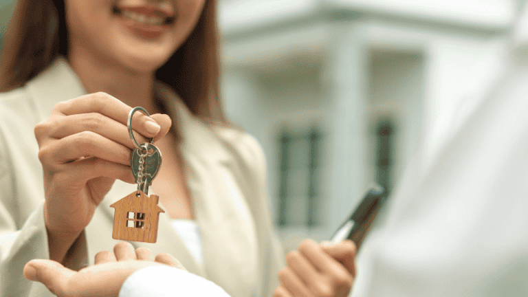 A landlord hands over keys with a house-shaped keychain, symbolizing a new home for the renter.