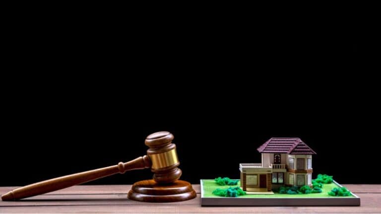 judge's gavel resting on wooden block and house model