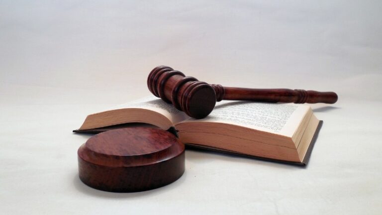 Wooden gavel resting on open law book background.