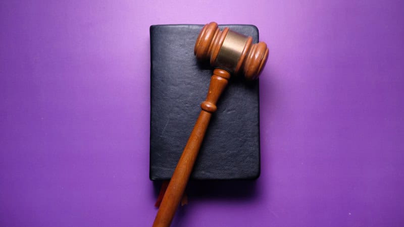 A Gavel and a Law Book on a Purple Background