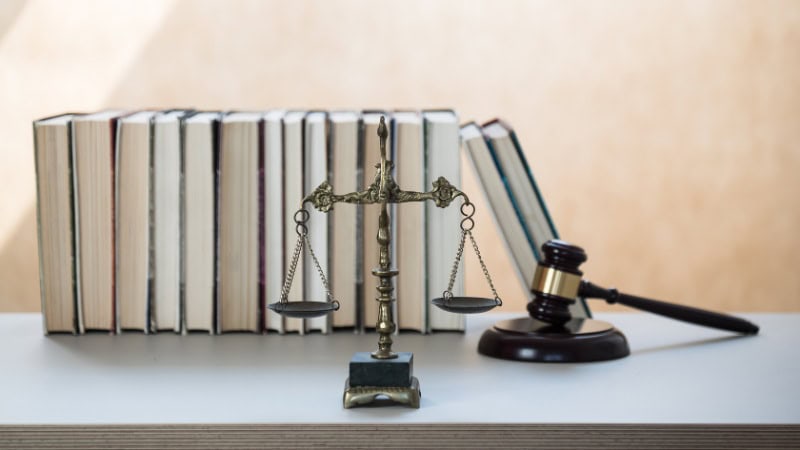 ustice scale and gavel with law books background.