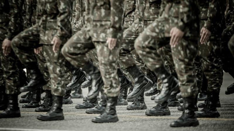 Soldiers marching in camouflage uniforms during a parade.