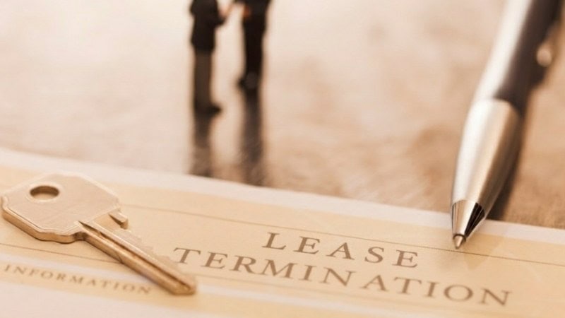 Lease termination document with key and pen on table.