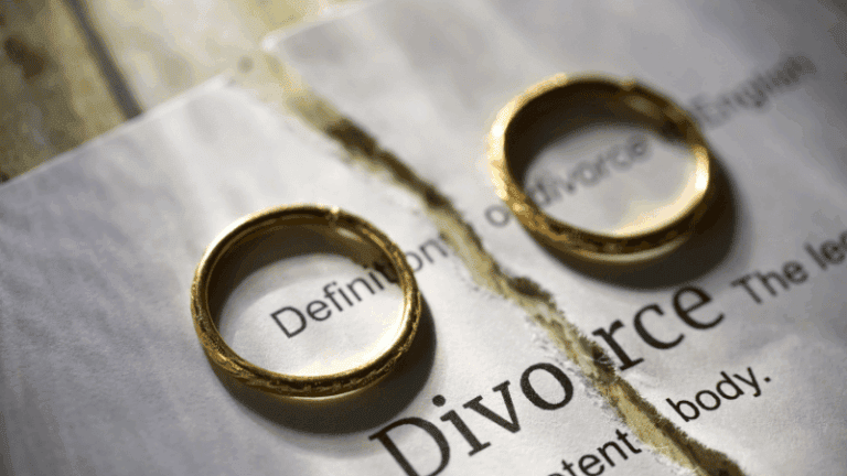 Two wedding rings placed on a torn page with the word “Divorce,” symbolizing the legal end of a marriage.
