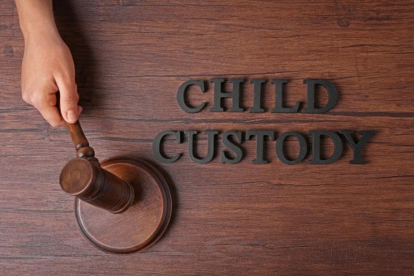 Judge’s gavel beside words “Child Custody” on wooden table.