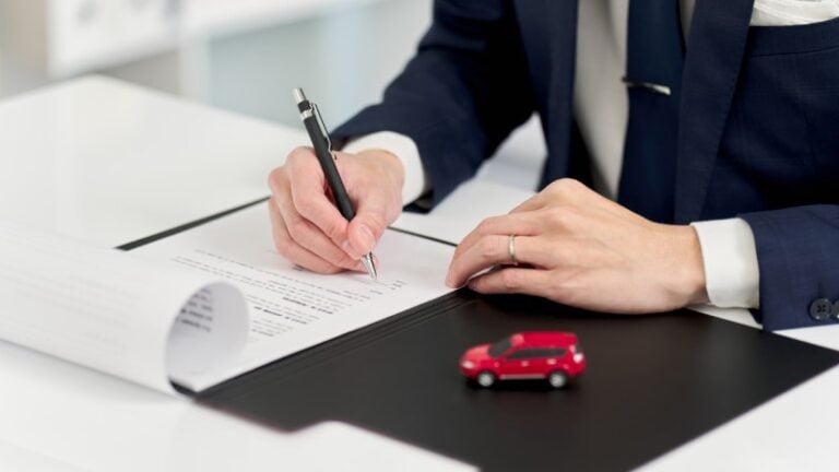 Person signing abandoned vehicle title paperwork during DMV ownership application process