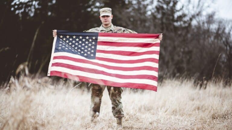 American soldier holding U.S. flag symbolizing servicemember protections under SCRA